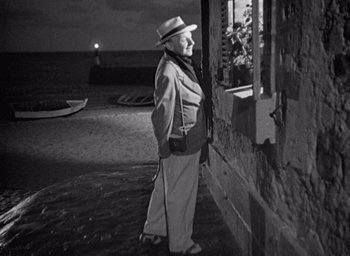 Movie still from “Monsieur Hulot's Holiday” (1953), directed by Jacques Tati – An old man standing next to a wall at night; Medium shot, High angle
