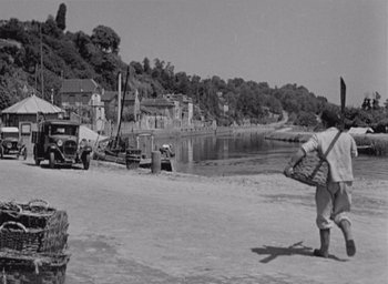 Movie still from “Monsieur Hulot's Holiday” (1953), directed by Jacques Tati – A man walking on the beach near a river; Extreme Wide shot, High angle
