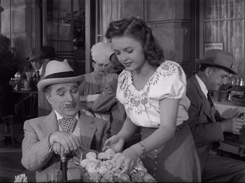 Movie still from “Monsieur Verdoux” (1947), directed by Charles Chaplin – An old photo of a man and a woman; Medium shot, High angle