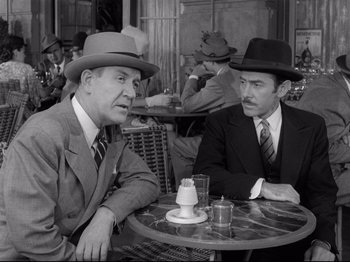 Movie still from “Monsieur Verdoux” (1947), directed by Charles Chaplin – Two men sitting at a table in front of each other wearing hats; Medium shot, High angle