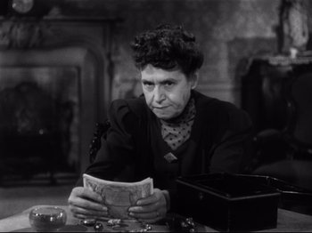Movie still from “Monsieur Verdoux” (1947), directed by Charles Chaplin – An older woman sitting at a table reading a newspaper; Close Up shot, High angle