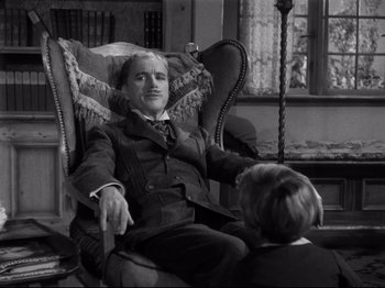 Movie still from “Monsieur Verdoux” (1947), directed by Charles Chaplin – An older man sitting in a chair talking to a young boy; Medium shot, Low angle