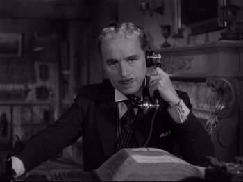 Movie still from “Monsieur Verdoux” (1947), directed by Charles Chaplin – An older man talking on a phone while sitting at a table; Close Up shot, Low angle