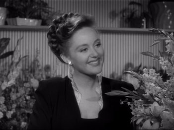 Movie still from “Monsieur Verdoux” (1947), directed by Charles Chaplin – A black and white photo of a woman in a black suit; Close Up shot, Over the shoulder angle