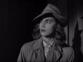 Movie still from “Monsieur Verdoux” (1947), directed by Charles Chaplin – A woman wearing a hat and a trench coat; Close Up shot, Low angle