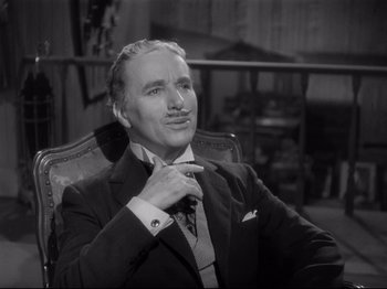 Movie still from “Monsieur Verdoux” (1947), directed by Charles Chaplin – An older man sitting in a chair with his hand on his chin; Close Up shot, High angle