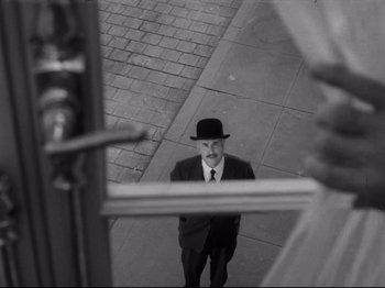 Movie still from “Monsieur Verdoux” (1947), directed by Charles Chaplin – A black and white photo of a man in a suit and a hat; Close Up shot, Over the shoulder angle