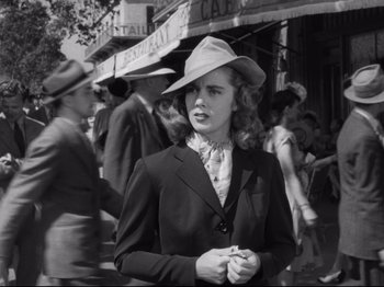 Movie still from “Monsieur Verdoux” (1947), directed by Charles Chaplin – A woman wearing a suit and hat in a crowd of people; Medium shot, Low angle