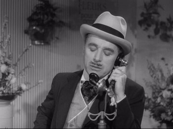 Movie still from “Monsieur Verdoux” (1947), directed by Charles Chaplin – A black and white photo of a man talking on a phone; Close Up shot, High angle