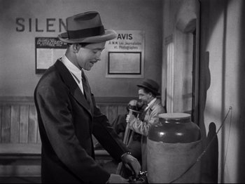 Movie still from “Monsieur Verdoux” (1947), directed by Charles Chaplin – A man in a suit and hat is holding a camera; Medium shot, High angle