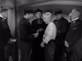 Movie still from “Monsieur Verdoux” (1947), directed by Charles Chaplin – A group of men standing next to each other in a room; Medium shot, High angle