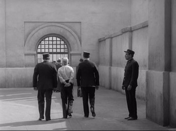 Movie still from “Monsieur Verdoux” (1947), directed by Charles Chaplin – A group of men standing next to each other in a building; Wide shot, High angle