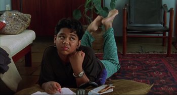 Movie still from “Monsoon Wedding” (2001), directed by Mira Nair – A young man is laying on the floor writing; Medium shot, High angle