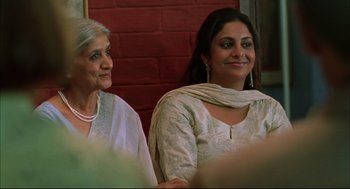 Movie still from “Monsoon Wedding” (2001), directed by Mira Nair – Two women sitting next to each other in front of a brick wall; Close Up shot, Low angle