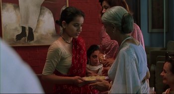 Movie still from “Monsoon Wedding” (2001), directed by Mira Nair – A woman holding a plate of food in front of a group of people; Medium shot, Low angle
