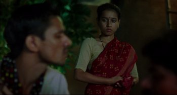 Movie still from “Monsoon Wedding” (2001), directed by Mira Nair – A woman in a red and yellow sari looking at a man in a white shirt; Medium shot, Over the shoulder angle