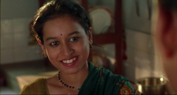 Movie still from “Monsoon Wedding” (2001), directed by Mira Nair – A young woman smiles brightly while wearing a green sari; Close Up shot, High angle