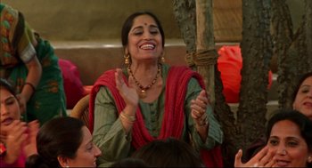 Movie still from “Monsoon Wedding” (2001), directed by Mira Nair – A woman claps her hands while sitting at a table; Medium shot, High angle