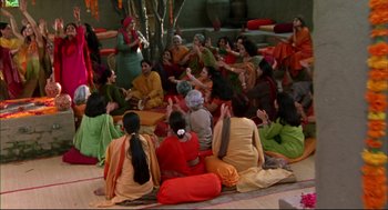 Movie still from “Monsoon Wedding” (2001), directed by Mira Nair – A group of people sitting in a circle with their hands raised; Wide shot, High angle