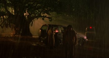 Movie still from “Monsoon Wedding” (2001), directed by Mira Nair – A group of people standing next to a car; Extreme Wide shot, Low angle