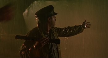Movie still from “Monsoon Wedding” (2001), directed by Mira Nair – A man in a raincoat and hat holding a gun; Medium shot, Low angle