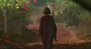 Movie still from “Monsoon Wedding” (2001), directed by Mira Nair – A person walking down a dirt road near trees; Wide shot, Low angle