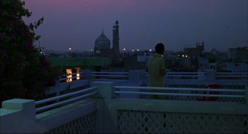 Movie still from “Monsoon Wedding” (2001), directed by Mira Nair – A person standing on a balcony looking at a building; Wide shot, Low angle