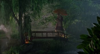 Movie still from “Monsoon Wedding” (2001), directed by Mira Nair – A person holding an umbrella over a bridge in the rain; Extreme Wide shot, Low angle
