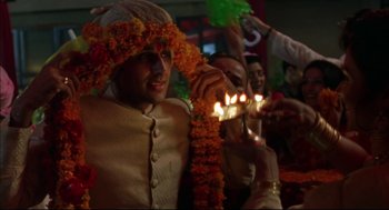 Movie still from “Monsoon Wedding” (2001), directed by Mira Nair – A young man wearing a garland of orange flowers and holding a lit candle; Close Up shot, High angle