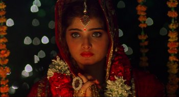 Movie still from “Monsoon Wedding” (2001), directed by Mira Nair – A woman in a red and gold dress and a gold head piece; Close Up shot, High angle