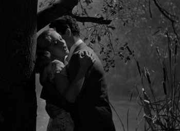 Movie still from “Moonrise” (1948), directed by Frank Borzage – A man and a woman embracing near a tree; Medium shot, Low angle