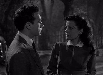 Movie still from “Moonrise” (1948), directed by Frank Borzage – A man and a woman standing next to each other in front of trees; Medium shot, High angle