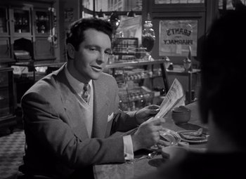 Movie still from “Moonrise” (1948), directed by Frank Borzage – A black and white photo of a man sitting at a table with a newspaper; Medium shot, Over the shoulder angle