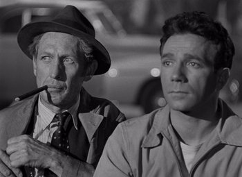 Movie still from “Moonrise” (1948), directed by Frank Borzage – A man smoking a pipe next to another man in a hat; Close Up shot, Over the shoulder angle