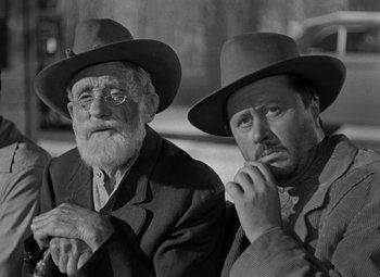 Movie still from “Moonrise” (1948), directed by Frank Borzage – A couple of men wearing hats and sitting next to each other; Medium shot, Low angle