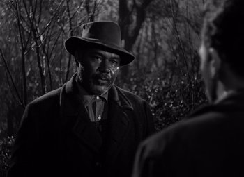 Movie still from “Moonrise” (1948), directed by Frank Borzage – A man wearing a hat standing next to another man in a forest; Close Up shot, Over the shoulder angle