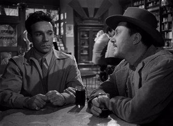 Movie still from “Moonrise” (1948), directed by Frank Borzage – Two men are sitting at a table in a bar; Medium shot, Over the shoulder angle