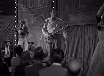Movie still from “Moonrise” (1948), directed by Frank Borzage – An old photo of a man speaking at an event; Wide shot, Low angle