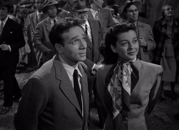 Movie still from “Moonrise” (1948), directed by Frank Borzage – A man and a woman standing next to each other in a crowd; Medium shot, High angle