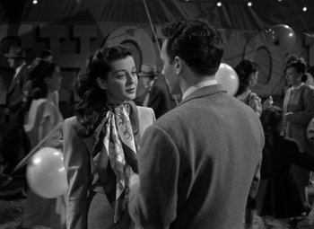 Movie still from “Moonrise” (1948), directed by Frank Borzage – A man and a woman talking to each other in front of a crowd; Medium shot, Over the shoulder angle