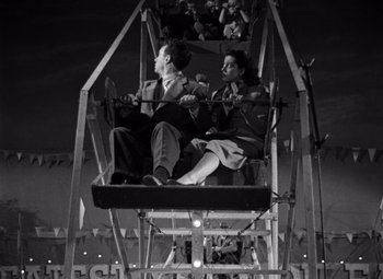 Movie still from “Moonrise” (1948), directed by Frank Borzage – A man and a woman sitting in a ferris wheel; Wide shot, Low angle