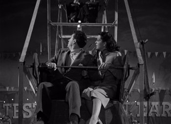 Movie still from “Moonrise” (1948), directed by Frank Borzage – A man and a woman sitting in a ferris wheel at night; Medium shot, Low angle