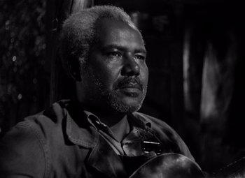 Movie still from “Moonrise” (1948), directed by Frank Borzage – A black and white photo of a man holding a guitar; Close Up shot, Low angle