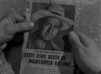Movie still from “Moonrise” (1948), directed by Frank Borzage – A person holding up a newspaper with a picture of a man; Close Up shot, High angle