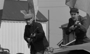 Movie still from “Morgan!” (1966), directed by Karel Reisz – A man in a hat holding a gun; Medium shot, Low angle