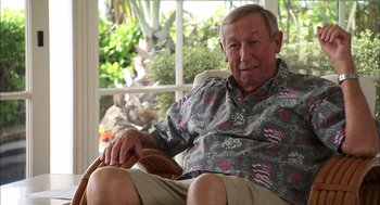 Movie still from “Morning Light” (2008), directed by Mark Monroe – An older man sitting in a chair in front of a window; Medium shot, Over the shoulder angle