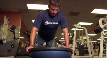 Movie still from “Morning Light” (2008), directed by Mark Monroe – A man in a blue t - shirt is pushing a ball; Medium shot, Low angle