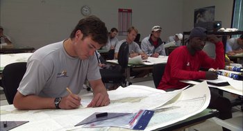 Movie still from “Morning Light” (2008), directed by Mark Monroe – A group of people sitting at a table working on a map; Medium shot, High angle