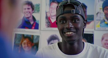 Movie still from “Morning Light” (2008), directed by Mark Monroe – A man wearing a hat and smiling for the camera; Close Up shot, Low angle