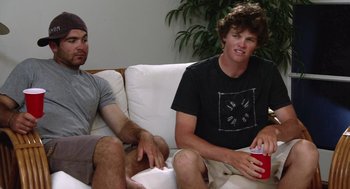 Movie still from “Morning Light” (2008), directed by Mark Monroe – Two young men sitting on a white couch; Medium shot, Low angle
